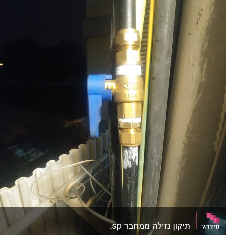 שסתום פליז עם ידית כחולה על צינור